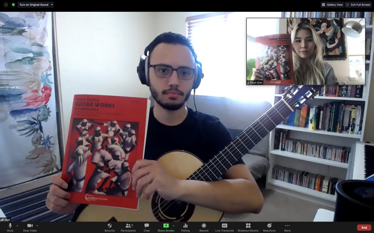 Matt and Jiji holding up copies of a published collection of guitar music by Frantz Cassius,