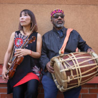 Two musicians with a violin and drum respectively look off into the distance
