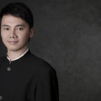 A Thai composer posing with a dark background