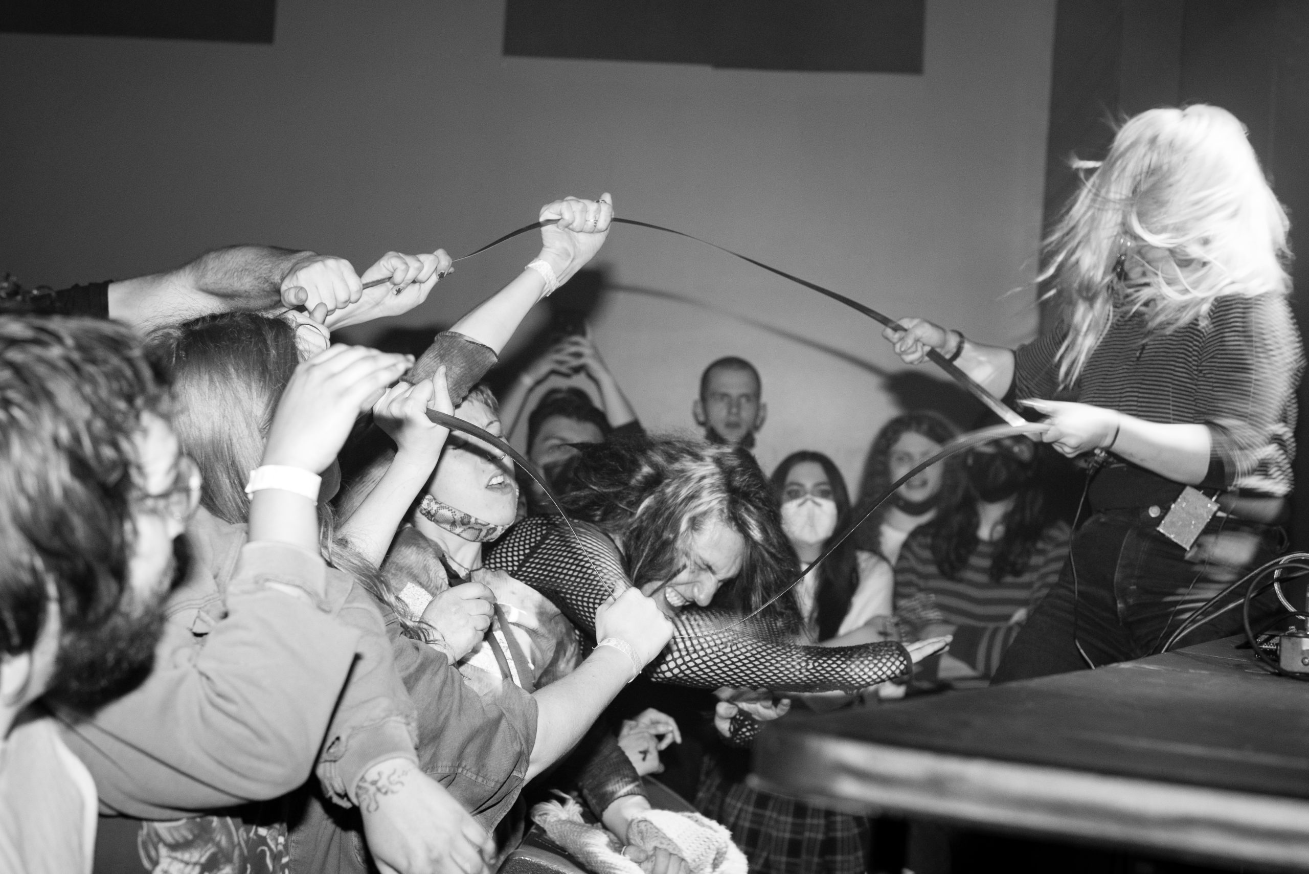 Victoria Shen creating sounds from pulling a long wire that stretches across a crowded room.