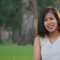 An outdoor photo of an AAPI woman in a white, cream top