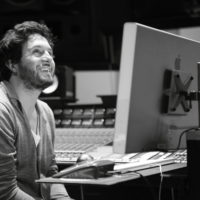 A black and white photo of a Latinx man at a computer, smiling