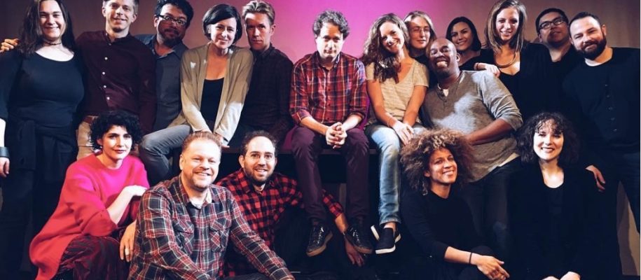 A group photo of the Experiments in Opera team against a dark pink background