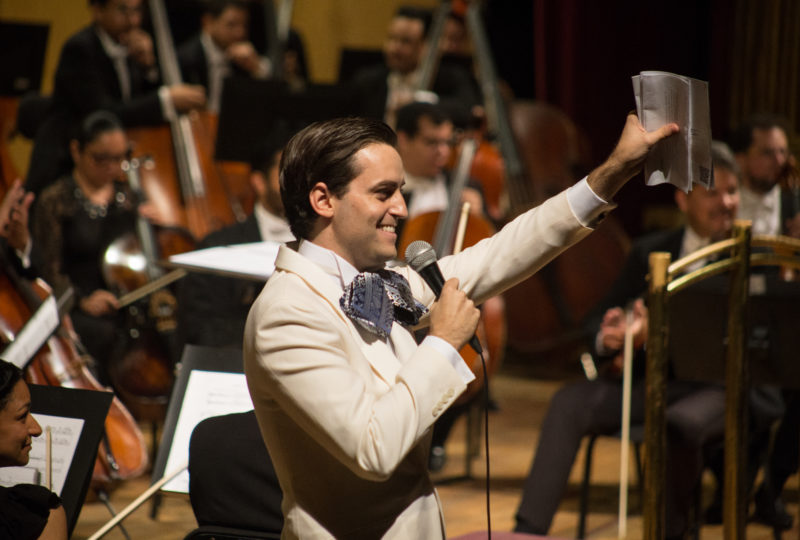 A Latinx man waving from the orchestra stage