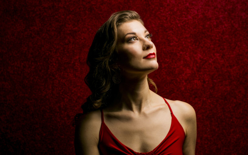 A woman in red against a red background, looking into the distance