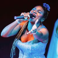 A black woman with cornrows wearing a Chico Lecca dress