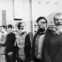 Black and white disorted image of 6 caucasian men