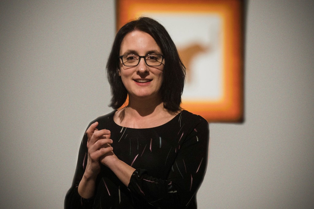 Stacey Barelos standing in front of a painting.