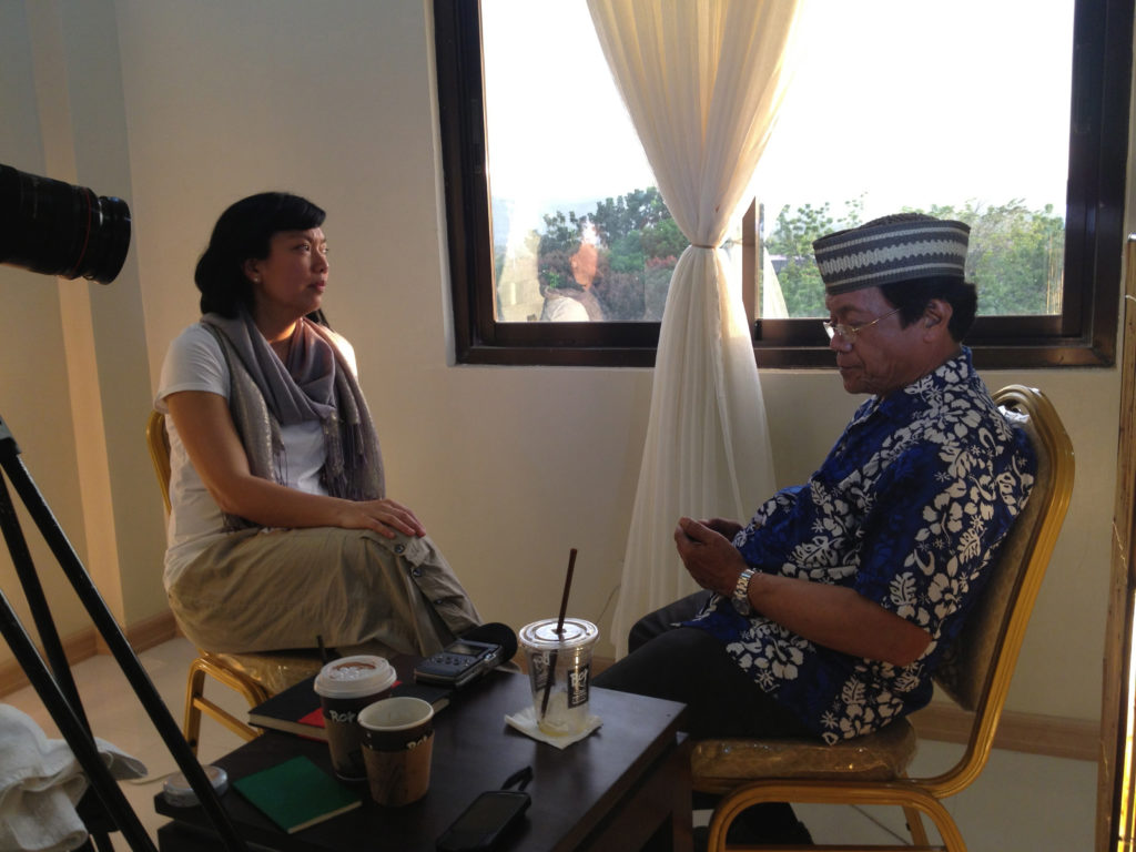 Susie Ibarra sitting across from Danongan Kalanduyan with an audio recorder and video recorder near a window.