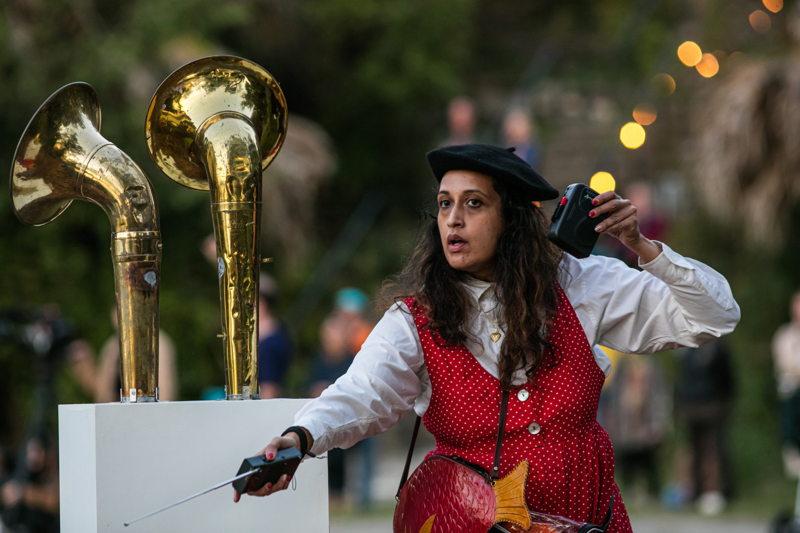 A costumed Tara Bhattacharya holding a small radio and standing near a group of foghorns.
