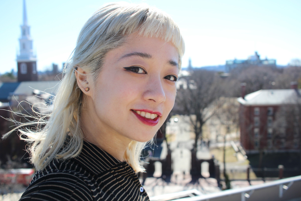 Victoria Shen on a rooftop with buildings in the town she is in visible in the background. 